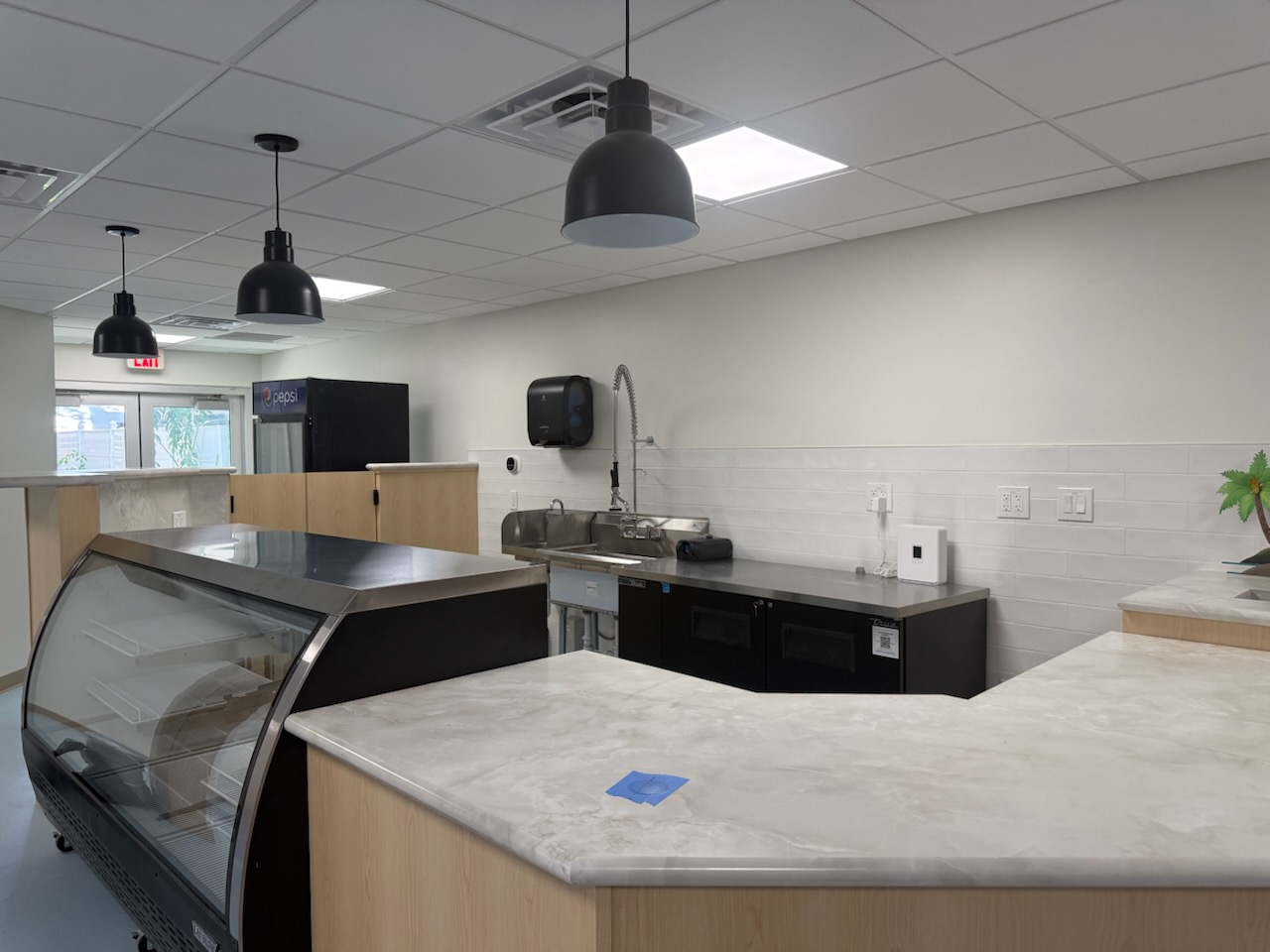 Haven’s juice-bar counter with pale wood cabinetry and black pendant lights